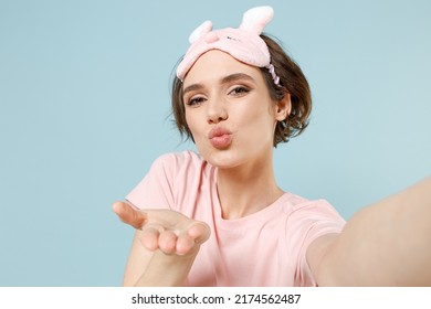 Close Up Young Woman In Pajamas Jam Sleep Eye Mask Rest Relaxing At Home Do Selfie Shot Mobile Phone Blow Air Kiss Isolated On Pastel Blue Background Studio Portrait. Good Mood Night Bedtime Concept