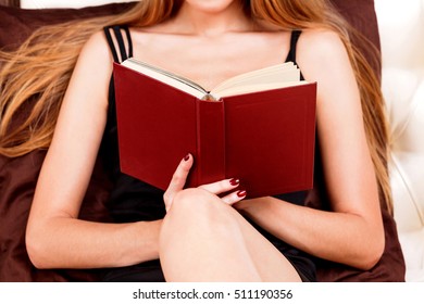 Close Up Of Young Woman Reading Book In Bed