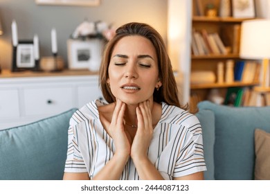 Close up of young woman rubbing her inflamed tonsils, tonsilitis problem, cropped. Woman with thyroid gland problem, touching her neck, girl has a sore throat - Powered by Shutterstock