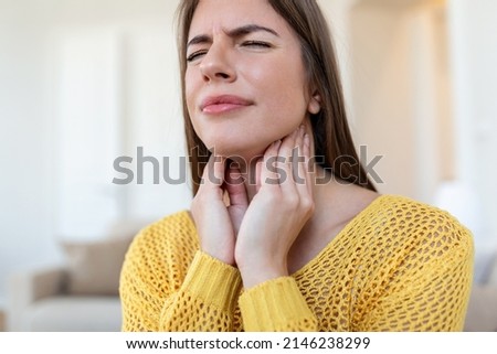Close up of young woman rubbing her inflamed tonsils, tonsilitis problem, cropped. Woman with thyroid gland problem, touching her neck, girl has a sore throat