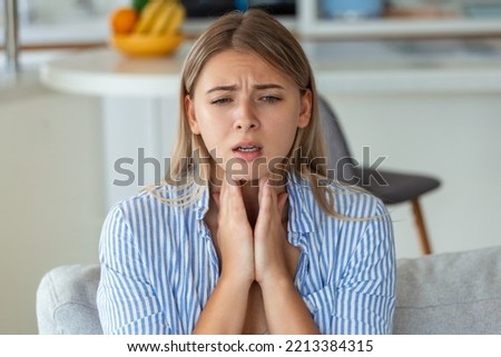 Close up of young woman rubbing her inflamed tonsils, tonsilitis problem, cropped. Woman with thyroid gland problem, touching her neck, girl has a sore throat