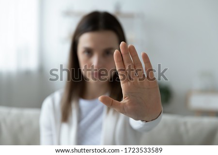 Close up of young woman show stop gesture sign by hand saying no to domestic violence or abuse, determined millennial female protest against abortion or discrimination, nonverbal language concept