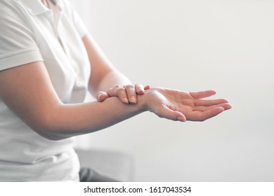 Close up of a young woman sitting on a sofa holding her wrist. hand injury, pain. Pain in the joints of the hands. Carpal tunnel syndrome. Healthcare and medical concept.