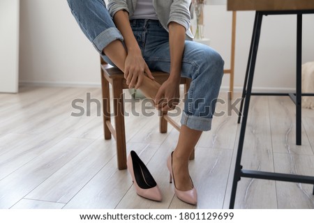 Close up young woman sitting on chair, taking off high heel shoes, massaging tired foot relieving pain ache in office. Exhausted millennial lady feeling feet discomfort, wearing narrow footwear. 商業照片 © 