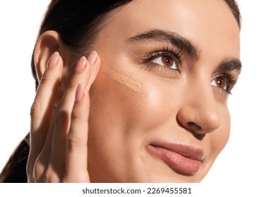 close up of young woman with soft skin applying makeup foundation on cheek with fingers isolated on white