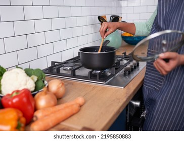 Close Up Of Young Woman Stirring A Pot Of Food On Gas Stovetop