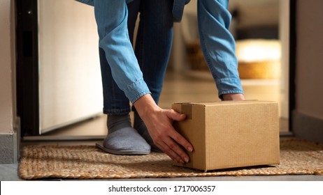 Close Up Of An Young Woman Is Taking From A Doormat A Parcel Delivered By Mailman In Her Home. Concept Of Courier, Delivery, E-commerce, Online Shopping