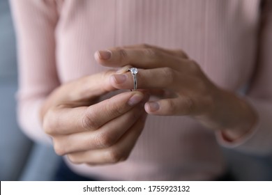 Close up young woman taking off wedding ring, divorce concept, female hands holding engagement ring, cheated girl break up with boyfriend or husband, family split, bad relationship - Powered by Shutterstock