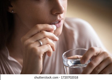 Close Up Young Woman Taking White Round Pill, Holding Water Glass, Unhealthy Female Taking Painkiller To Relieve Headache, Antidepressant Or Antibiotic Medicine, Emergency Treatment