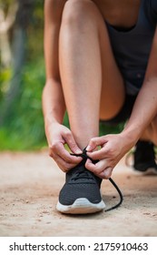 Close up of young woman tying her shoe laces in the park