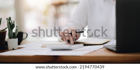 Close up young woman using calculator, managing household monthly budget, summarizing taxes or bills, planning future investments, doing financial affairs at home, accounting bookkeeping concept.
