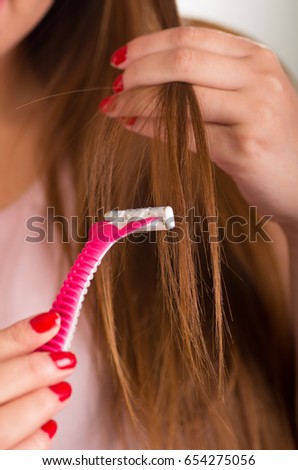Close up of a young woman using a shaver on her hair, bath background