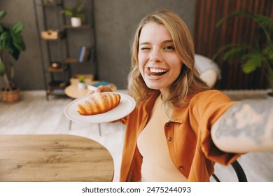 Close up young woman wear orange shirt do mobile cell phone selfie shot wink sits alone at table in coffee shop cafe relax rest at restaurant in free time indoors. Freelance office business concept - Powered by Shutterstock