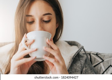 Close Up Of Young Woman Wearing Sweater Sipping Coffee Or Tea From White Mug In The Morning