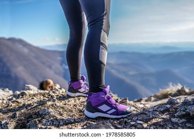 Close up of young woman's legs with leggings and hiking shoes on top of the mountain