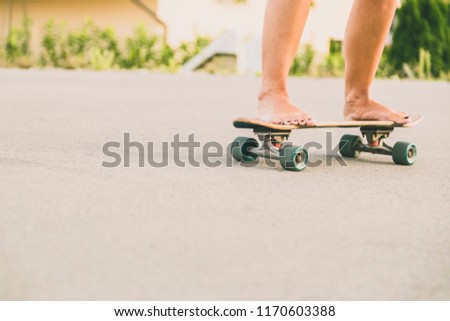Close up of young woman`s legs riding skateboard bare feet