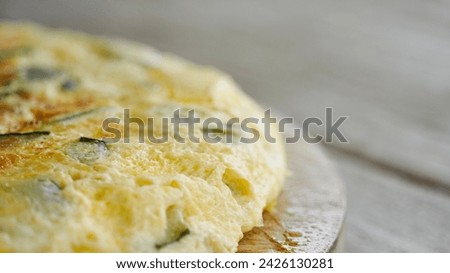 Close up zucchini omelet on white wooden table with space for text.
