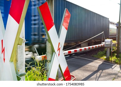 Closed Barrier At The Railroad Crossing With St. Andrew Cross, Visible Blurred Blue Wagon In Motion.