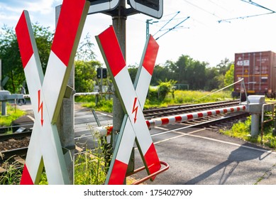 Closed Barrier At The Railway Crossing With St. Andrew Cross, Visible Blurred Red Wagon In Motion.