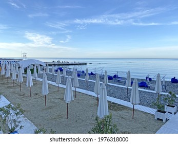 Closed Beach Umbrellas On A Pebble Beach. Sea Beach In The Early Morning Hour. No People 