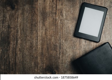 A Closed Bible And An Ebook On A Wooden Texture. Bible Study Desk