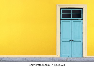 Closed blue wooden door on yellow wall background