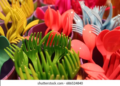 Closed up bunch of multi-color plastic ware cutlery with selective focus 