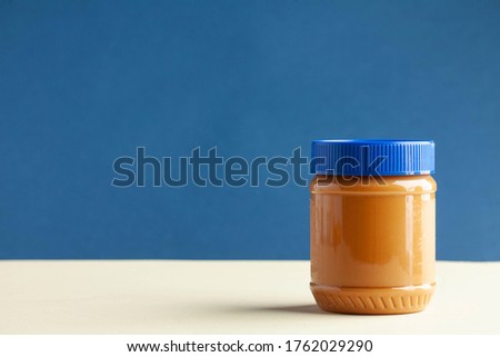 Closed can of peanut butter on a colored background. American culture. Breakfast, dessert for vegetarians. Copy space.