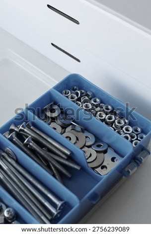 A closed cardboard toolbox and an open plastic box for storing small bolts and nuts 