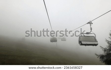 closed chairlift without people immersed in fog in the mountains