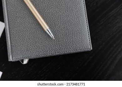 Closed diary with gray leather cover. gold pen on black background. Diary and planner notebook to plan agenda, reminder, schedule, daily appointment, desk management.