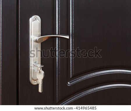 Closed door handle. Door lock with keys. Dark brown wooden door closeup. Modern interior design, door handle. New house concept. Real estate. 
