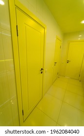 Closed Door In New Bathroom In Hospital. Yellow Clinic Light. Tilled Walls In Toilet Room. Closeup.