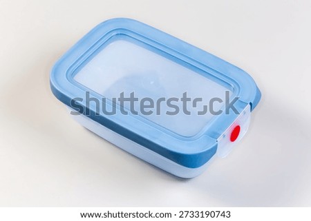 Closed empty reusable blue plastic leakproof translucent lunch box with silicone seals and strong fastener on a grey background