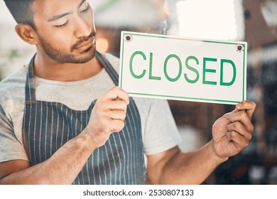 Closed, entrepreneur and man with sign, glass and sad for bankruptcy of small business and serious. Store, door and person in hospitality, window and message on entrance, apron and waiter in cafe - Powered by Shutterstock