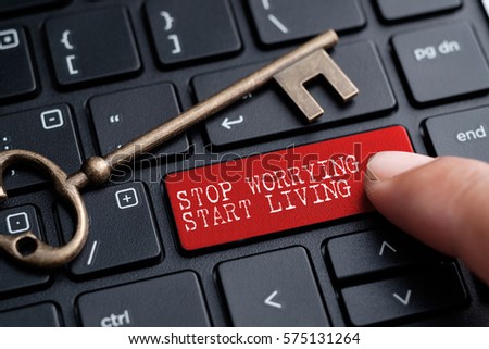 Closed up finger on keyboard with word STOP WORRYING, START LIVING.
