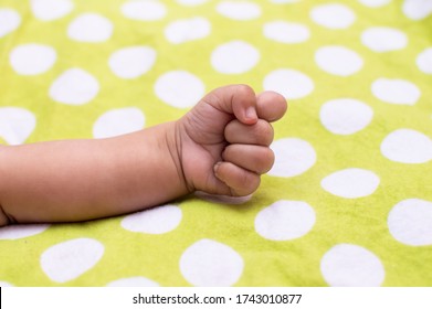 A Closed Fist And Forearm Of An Infant On A Polka Dotted Background