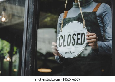 Closed. friendly waitress wearing protection face mask turning open sign board on glass door in modern cafe coffee shop, cafe restaurant, retail store, small business owner, food and drink concept - Powered by Shutterstock