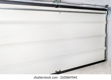 A Closed Garage Door With An Electric Drive, Four Sections, A View From The Inside Of The Garage.