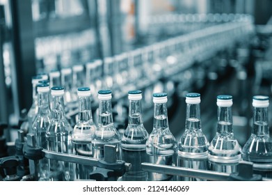 Closed glass bottles of upscale vodka transported by line - Shutterstock ID 2124146069