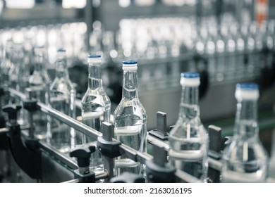 Closed glass bottles of upscale vodka transported by line - Shutterstock ID 2163016195
