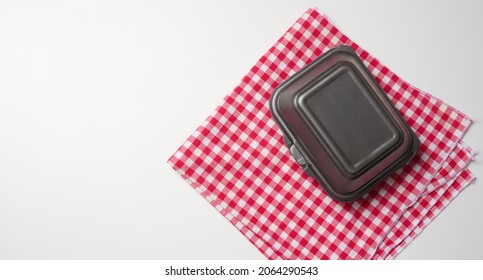 Closed Gray Disposable Container And A Red Napkin On A White Table, Top View