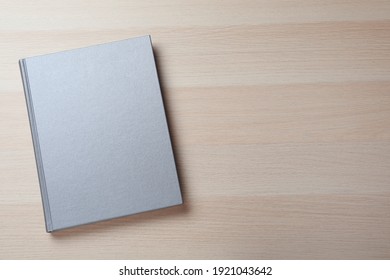 Closed Grey Book With Hard Cover On Wooden Table, Top View. Space For Text