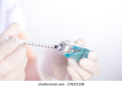 Closed Up Hand Of Nurse Fills Syringe From Injection Vial On White