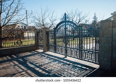 Closed iron gates and fence near the road from paving slabs