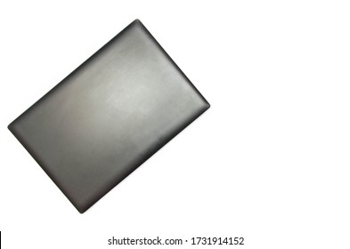 Closed Laptop On A White Background. View From Above. The Laptop Lies Sideways In The Upper Left Corner. Black, Graphite, Gray, Dark Laptop