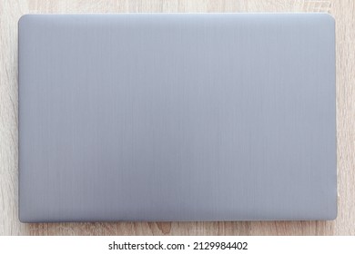 Closed Laptop Top View, Silver Color On A Wooden Table