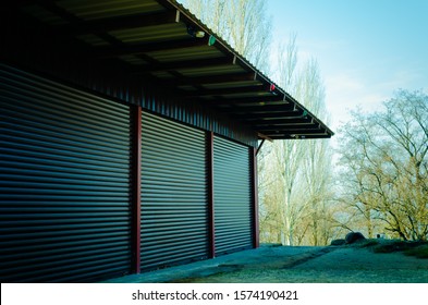 Closed metal doors of self-storage warehouses. Warehouse building on the background of autumn poplars without foliage. Side view. Landscape photo location.