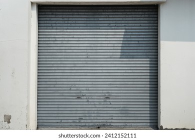 Closed metal grate rolling door of the warehouse storage or service garage. View from in front of the building, industrial building place. - Powered by Shutterstock