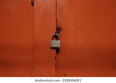 Closed metal red door with silver padlock key. Minimalist red background. vintage and rustic background.